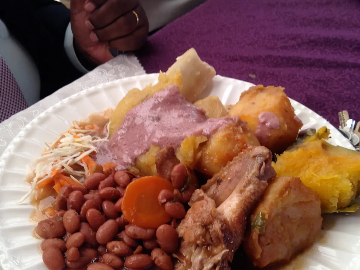 A plate of rice, beans, pork and sweet potato on a white tablecloth